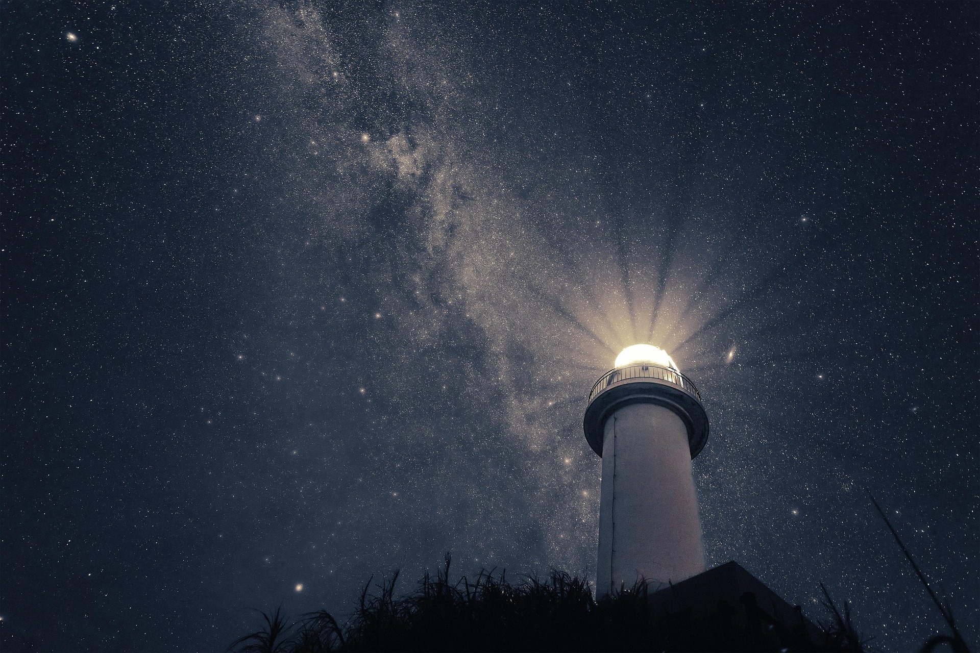Lighthouse with bright beam against a starry night sky